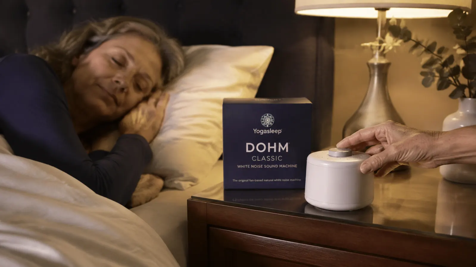 Close-up of a hand turning the volume dial on the top of the Yogasleep Dohm Classic